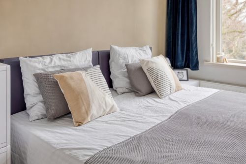 Stilvoller CUBIQZ-Bezug für das Kopfteil eines Doppelbetts, der ein Kartonbett in eine realistische Schlafzimmerpräsentation verwandelt.